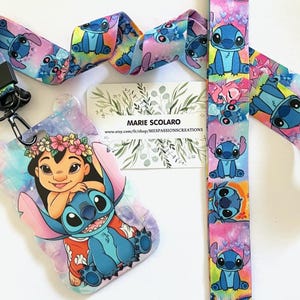 Może przedstawiać: Zestaw smyczy i uchwytu na identyfikator z postaciami Lilo i Stitch. Smycz i uchwyt na identyfikator mają kolorowy wzór z ilustracjami Stitcha. Uchwyt na identyfikator przedstawia Lilo i Stitch. Zestaw zawiera czarny zatrzask i kartę z tekstem "MARIE SCOLARO".