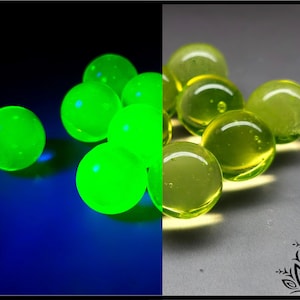 Puede incluir: Imagen dividida: esferas verdes brillantes sobre fondo azul oscuro y esferas amarillo-verdosas sobre fondo gris. Las esferas parecen ser canicas de vidrio, posiblemente decorativas o para jugar, con un aspecto luminoso.