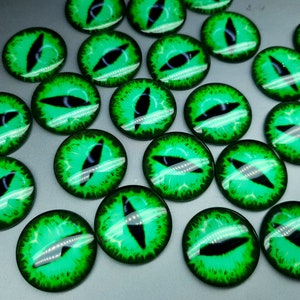 May include: A collection of circular glass cabochons featuring a vibrant green iris with a sharp, vertical black pupil, resembling a reptilian or feline eye. Each piece has a smooth, domed surface with detailed radial patterns in shades of bright lime and emerald green.