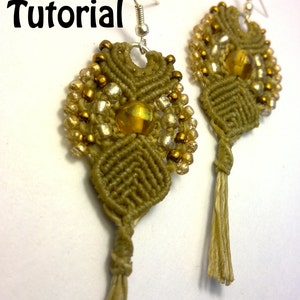 May include: A pair of handmade macrame earrings in olive green, adorned with gold and silver beads and a central amber-colored bead. The earrings have a tassel at the bottom and silver hooks. The word "Tutorial" is written in black.