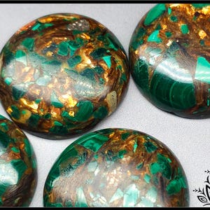 May include: Close-up of several polished, round gemstones. The stones feature a mix of green, brown, and gold colours. The gemstones have a mosaic-like appearance with a glossy finish. The overall theme is natural gemstones.