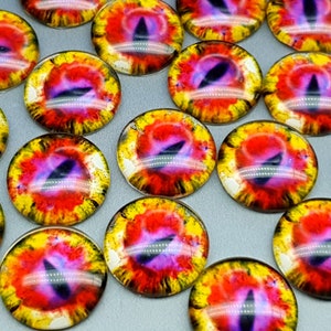 May include: A collection of circular glass cabochons featuring a detailed dragon eye design. Each piece displays a vibrant iris with a blend of yellow, orange, and red hues, centred by a dark, vertical, slit-shaped pupil with purple accents.