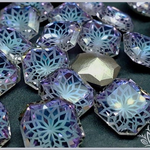 May include: A collection of faceted, square-shaped glass beads featuring a translucent light purple hue and an iridescent finish. Each bead displays a white, intricate, geometric starburst pattern etched onto the surface, with one solid silver-toned bead.