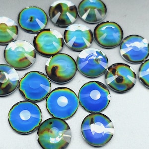 May include: A collection of round, faceted glass cabochons featuring a vibrant iridescent finish. Each piece displays a shifting color palette of bright blue, deep green, and dark brown tones with a reflective surface that catches the light.