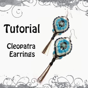 Könnte beinhalten: Ein Paar Cleopatra-Ohrringe mit Makramee-Design in Blau, Weiß und Schwarz. Die Ohrringe haben eine zentrale Perle und hängende Quasten. Der Text "Tutorial" und "Cleopatra Earrings" ist in Schwarz geschrieben.