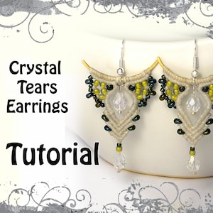 Peut inclure: Une paire de boucles d'oreilles en forme de larme de cristal avec un design en macramé. Les boucles d'oreilles sont faites de cordon blanc, de perles vertes et noires et de larmes de cristal transparentes. Les boucles d'oreilles sont suspendues à des crochets d'oreille en argent.
