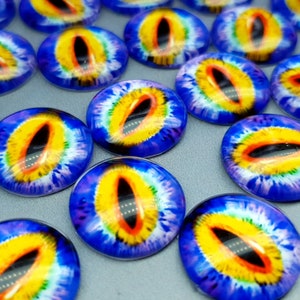 May include: A collection of round glass cabochons featuring a realistic animal eye design. Each piece displays a vibrant yellow iris with a thin orange ring, a black vertical pupil, and a deep blue outer edge with radial patterns.