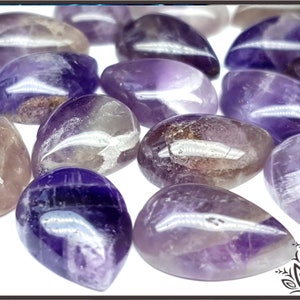 Puede incluir: Una colección de piedras de amatista pulidas en varios tonos de púrpura. Las piedras tienen forma de lágrima y un acabado liso y brillante.