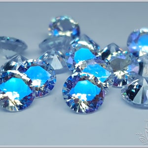 May include: A collection of round, faceted clear gemstones with an iridescent finish that reflects vibrant blue and purple light. Each stone features a brilliant cut with multiple triangular facets that create a sparkling, prismatic effect.