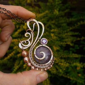 Peut inclure: Un pendentif en fil de cuivre enroul&eacute; avec une pierre d'am&eacute;thyste violette et des perles de cuivre. Le pendentif a la forme d'un tourbillon avec une petite pierre d'am&eacute;thyste en haut.