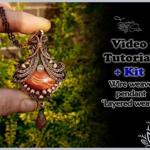 Op de afbeelding: Een koperen draadgewikkelde hanger met een rood-witte steen. De hanger zit aan een ketting en wordt vastgehouden door een hand. De afbeelding bevat de tekst "Video Tutorial + Kit Draad geweven hanger 'Gelaagd weven'".