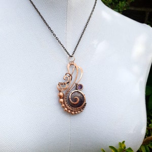 Peut inclure: Un collier avec un pendentif en fil de cuivre enroul&eacute; avec une pierre violette et un motif en spirale.
