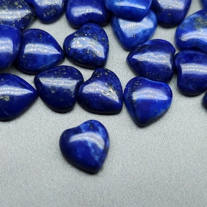 May include: A collection of heart-shaped lapis lazuli stones. The stones are a deep blue colour with flecks of gold pyrite.