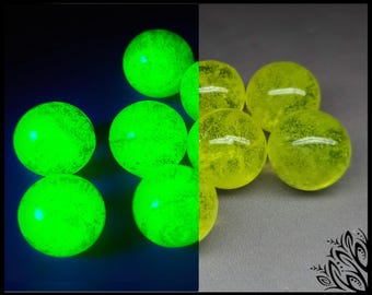 May include: A collection of spherical beads shown in a split-screen view. The left side displays the beads glowing with a bright neon green light against a dark background, while the right side shows the same beads in a translucent yellow hue.