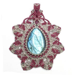 Op de afbeelding: Een zilveren en roze macram&eacute; hanger met een blauwe labradorite edelsteen in het midden. De hanger heeft de vorm van een stervorm.