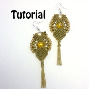 May include: Handmade macrame earrings in olive green with gold and clear beads, featuring a central yellow bead and a tassel. The word "Tutorial" is written in black. The earrings are suspended from silver-colored hooks.