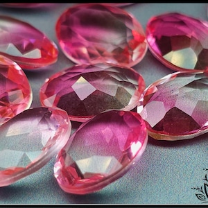 May include: A group of pink and clear faceted oval-shaped glass beads. The beads have a iridescent sheen.