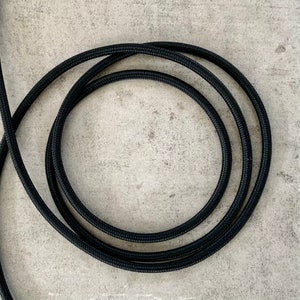 Könnte beinhalten: Schwarzes Stromkabel auf einer grauen Oberfläche.