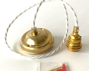 May include: A gold-colored pendant light fixture with a white twisted cord. The fixture includes a ceiling canopy, a bulb socket, and mounting hardware. The components are new and ready for installation.