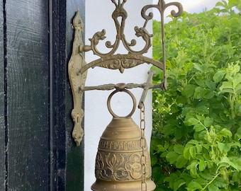 Gran campana antigua de latón fundido de monasterio con un soporte de pared ornamentado.