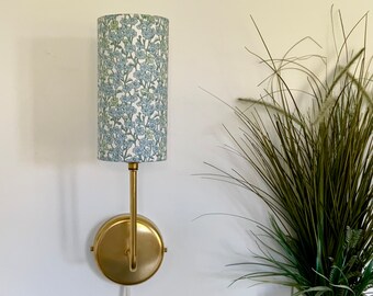Solid raw brass wall light, with plug in or hardwire options, and choice of Liberty fabric cylindrical lampshade. Danish design.