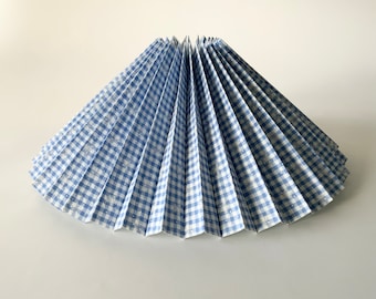 Può includere: Un paralume in gingham blu e bianco con un design plissettato.