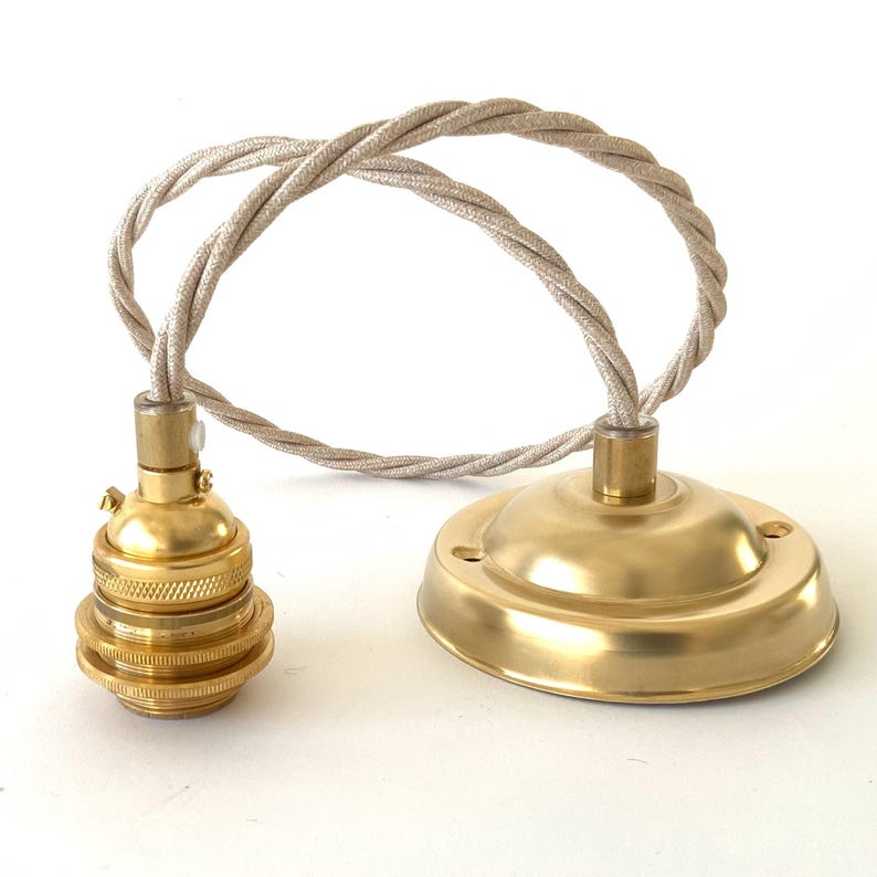May include: A brass-colored pendant light fixture with a matching ceiling canopy and a twisted fabric cord. The light socket is cylindrical and threaded. The canopy is round with screw holes.