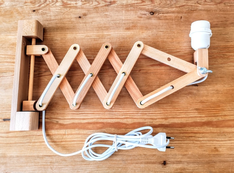 Puede incluir: Una l&aacute;mpara de pared de madera con un cable blanco y una toma de bombilla blanca. La l&aacute;mpara tiene un dise&ntilde;o plegable y se puede ajustar a diferentes &aacute;ngulos.