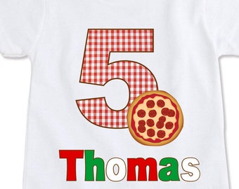 May include: White t-shirt featuring a large number 5 in a red and white gingham pattern, a pizza graphic, and the name "Thomas" in red and green. The shirt is designed for a child's fifth birthday.