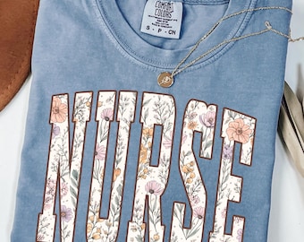 Camiseta Comfort Colors® estilo universitario para enfermeras con estampado gráfico y diseño floral de flores silvestres.