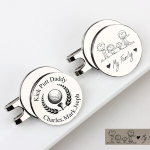 May include: Two silver golf ball markers. One marker has the text "Kick Putt Daddy" around a golf ball and tee graphic. The other marker has a family stick figure graphic and the text "My Family".