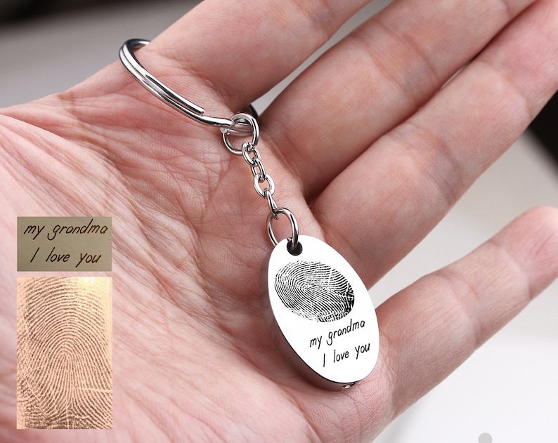 May include: Silver-colored keychain with an oval pendant featuring a fingerprint and the inscription "my grandma I love you." The keychain includes a key ring and a small chain. A separate card displays the fingerprint and text.