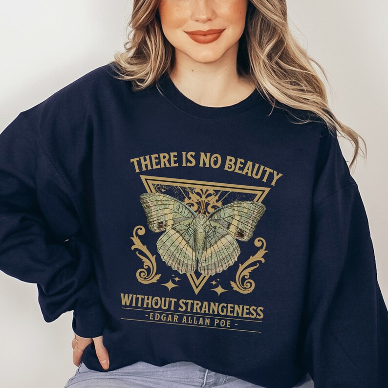 May include: Navy blue sweatshirt with a gold butterfly graphic and the text "There is no beauty without strangeness - Edgar Allan Poe -"