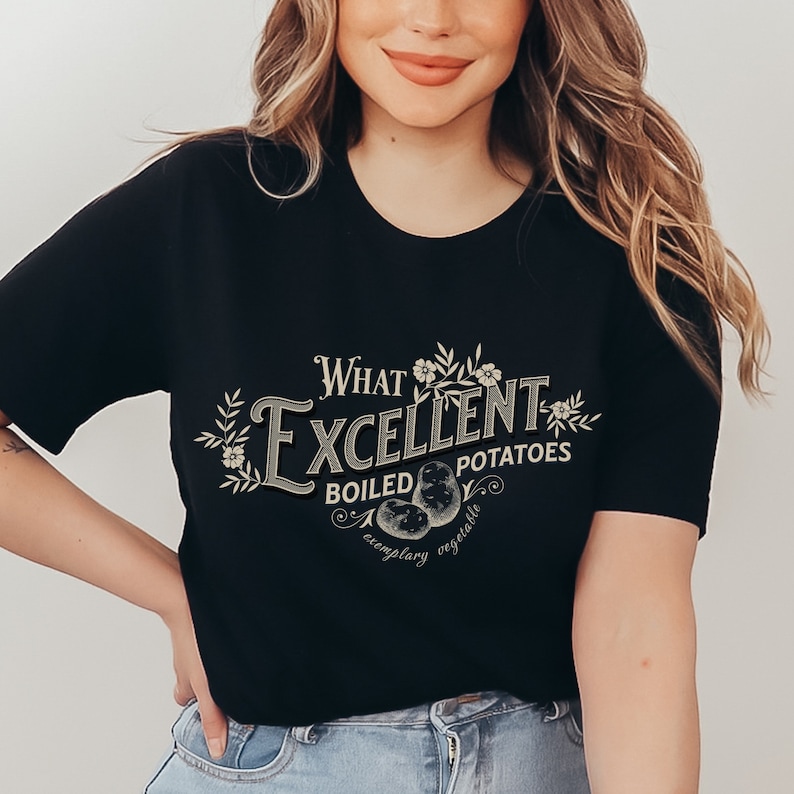 May include: A black t-shirt with a vintage-style graphic that reads "What Excellent Boiled Potatoes, Exemplary Vegetable". The graphic features a stylized illustration of potatoes and floral accents.