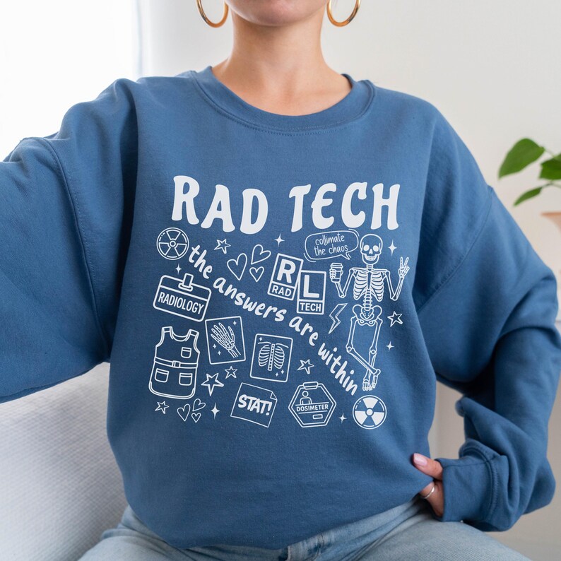 May include: A blue crewneck sweatshirt with the words "RAD TECH" in white, along with various medical-themed graphics. The design includes a skeleton, hearts, and the phrase "the answers are within."