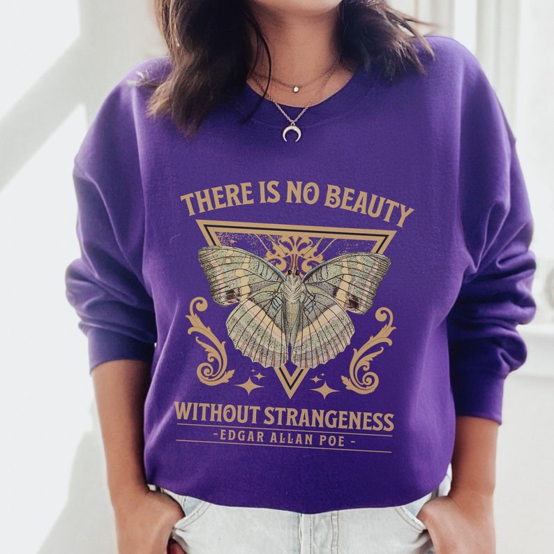 May include: Purple sweatshirt with a gold butterfly graphic and the text "There is no beauty without strangeness - Edgar Allan Poe -"