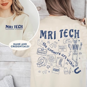 Może przedstawiać: Kremowa bluza z napisem "MRI TECH" w kolorze granatowym. Tył koszulki zdobią ilustracje o tematyce medycznej oraz fraza "the answers are within". Z przodu znajduje się imię "Mackenzie RT(R)(MR)" oraz "Name and Credentials!"