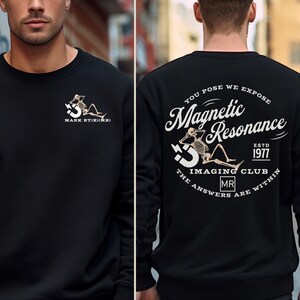 May include: Black sweatshirt with a white graphic print of a skeleton sitting on a 3D letter S. The text "Magnetic Resonance" is in a vintage style font with the words "You Pose We Expose" above and "Imaging Club" below. The text "ESTD 1977" is above the words "Imaging Club" and the text "The Answers Are Within" is below the words "Imaging Club".