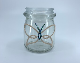 Airtight glass storage jar. Pastel white and aurora borealis black Diamond Dotz. Butterfly design. 3.5 in. high, 2.5 in. wide.
