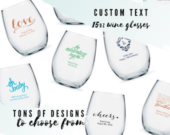 May include: A collection of clear 15 oz stemless wine glasses featuring various custom text designs in different colors and fonts. The glasses display phrases such as love, the adventure begins, oh baby, cheers, and happy birthday with dates.