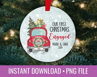 Può includere: Un addobbo natalizio rotondo, blu e bianco con un camioncino rosso che trasporta un albero di Natale e dei regali. L'addobbo ha il testo "Our First Christmas Engaged Mark & Gina 2019".