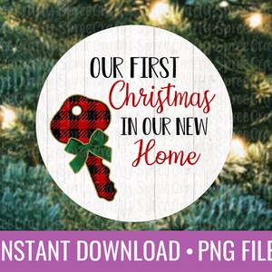May include: A white circle with a woodgrain background featuring a red and black plaid key with a green bow. The text "OUR FIRST Christmas IN OUR NEW Home" is written in black and red.