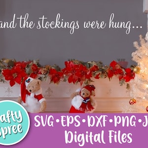 May include: A white Christmas tree with white lights and gold ornaments sits on a white mantel with a red and green garland. Two teddy bears wearing Santa hats are on the mantel. The text "and the stockings were hung..." is on the wall above the mantel. The text "Crafty Spree SVG EPS-DXF-PNG-JPG Digital Files" is at the bottom of the image.