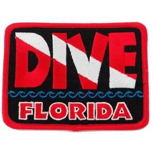 May include: Red, white, and blue embroidered patch with the word "DIVE" and the text "FLORIDA" below. The patch has a black background and a blue wave design.