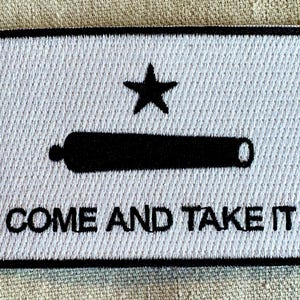 May include: White embroidered patch with a black cannon, a five-pointed star, and the text "COME AND TAKE IT".