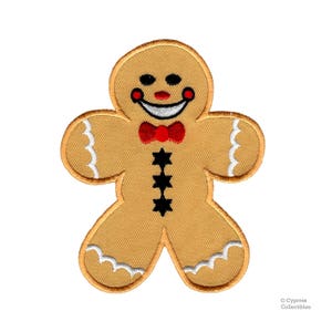 May include: A gingerbread man cookie with a red bow tie and a smiling face. The cookie is decorated with white icing and black buttons.