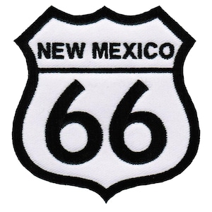 Puede incluir: Parche de señal de carretera de la Ruta 66 blanco y negro con el texto "NEW MEXICO" en la parte superior y el número "66" en una fuente negra grande.