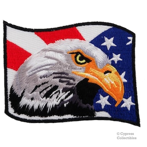 May include: Embroidered patch featuring a bald eagle's head with a yellow beak and eye, set against a waving American flag with red and white stripes and blue stars.