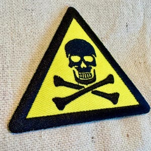 May include: Yellow triangle warning sign with a black skull and crossbones.