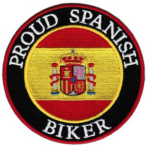 Puede incluir: Un parche redondo bordado con un borde negro y texto blanco que dice "Proud Spanish Biker". El centro del parche presenta la bandera de España con un escudo de armas.